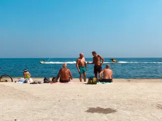 3 women and 2 men sitting on beach sand during daytime by Elena Rabkina courtesy of Unsplash.